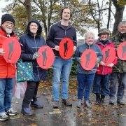 Group of councillors and volunteers holding red remembrance signs