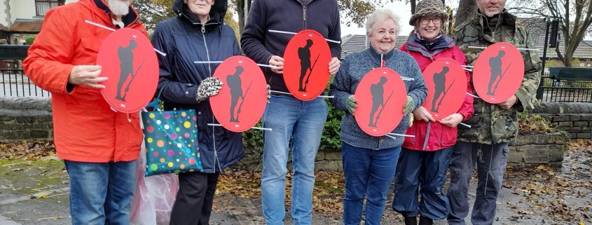 Group of councillors and volunteers holding red remembrance signs