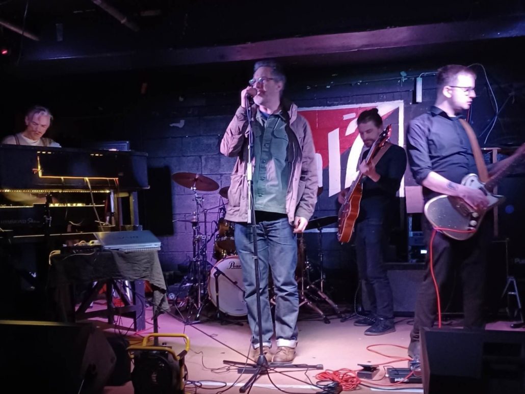 Music band. Man singing. Two men playing guitar