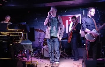 Music band. Man singing. Two men playing guitar